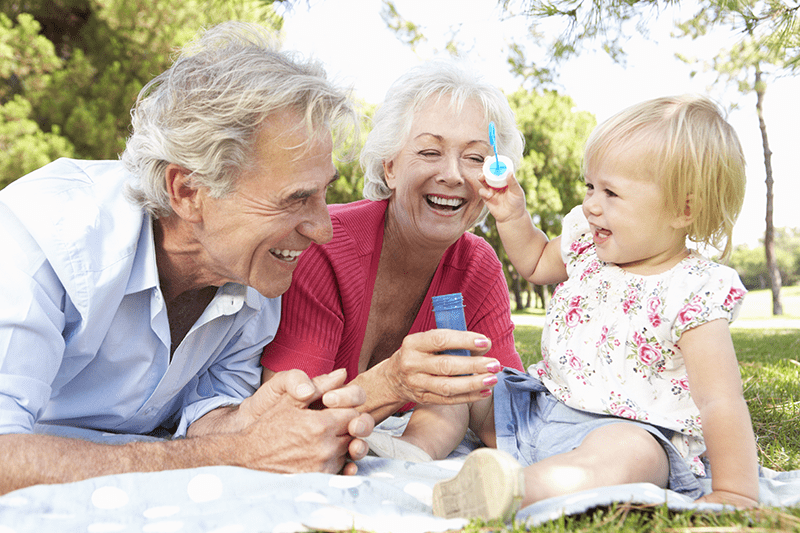 A couple laughing with a baby playing with bubbles.